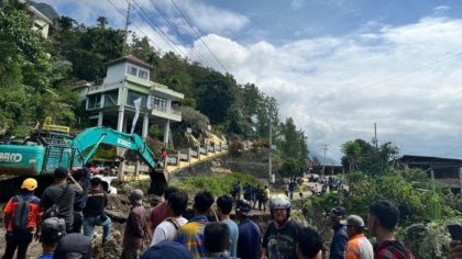 Warga dan petugas menggunakan alat berat untuk membersihkan material longsor yang menyebabkan jalan poros Enrekang-Toraja amblas di Bambapuang, Enrekang, Rabu (9/7).