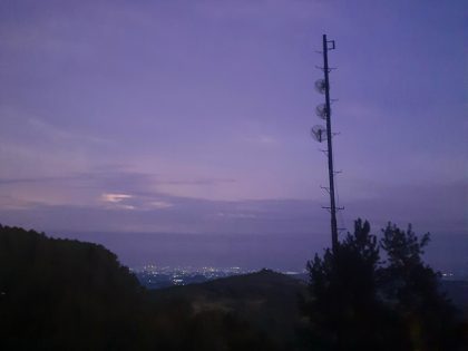 langit berkabut saat pagi dengan latar pegunungan dan menara pemancar di Sulawesi Selatan, mencerminkan suasana dingin.